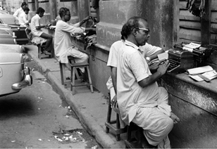 Photographer: Salim Paul; Source: Chitrabani Typewriting salesmen using building ledge, Calcutta, 1979.